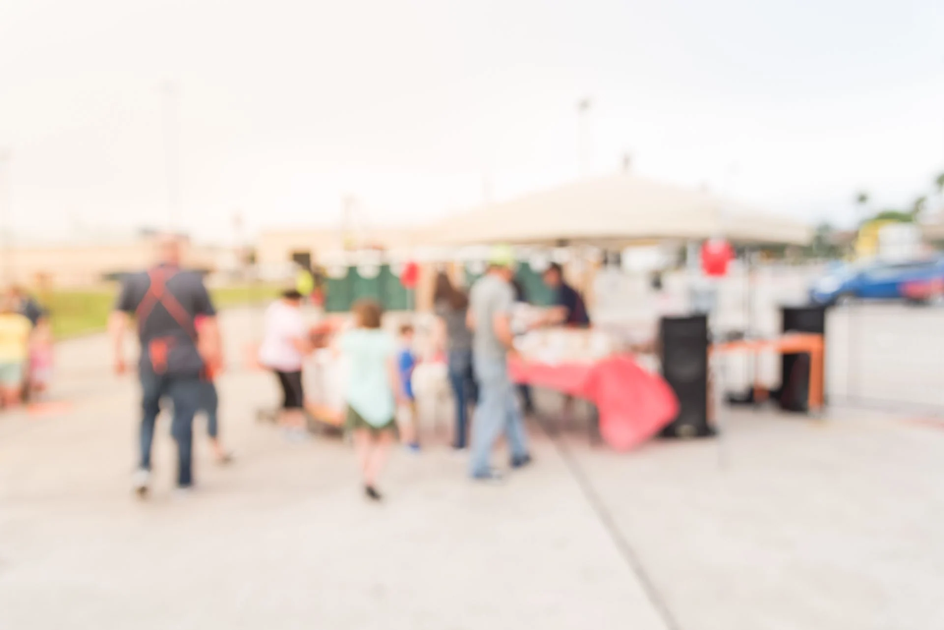 Blurred group of people enjoy barbecue at community event in Houston, Texas, USA. Defocused lunchtime cookout, tent outdoor party and festival concept.