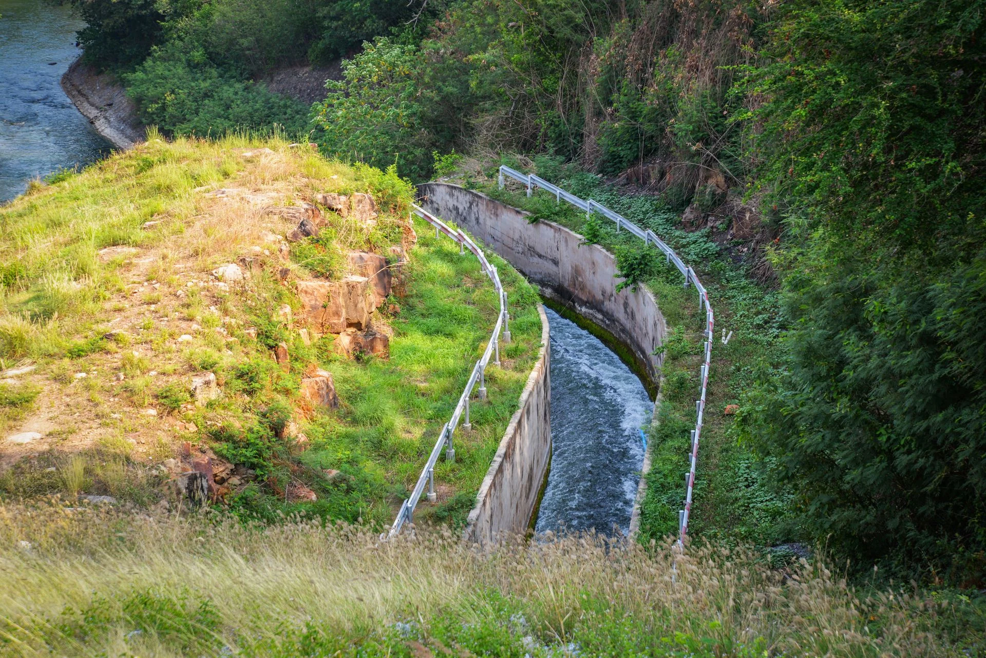 Drainage dam reservoir on hill with canal and drainage system water flow to river nature forest background 
